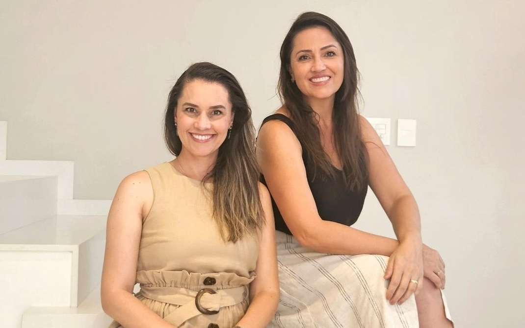 Thais e Denise sorrindo juntas no rodapé